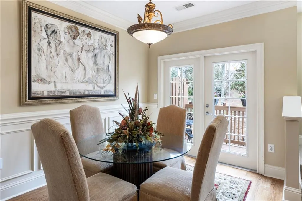Dining area with ornamental molding, wood finished floors, and wainscoting