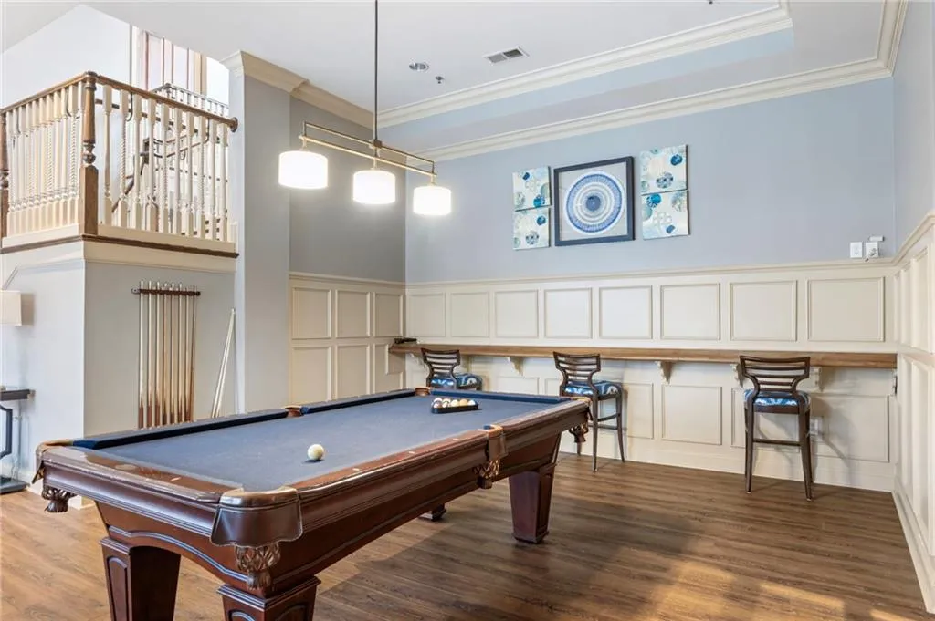 Rec room featuring a decorative wall, ornamental molding, billiards, dark wood-style floors, and wainscoting