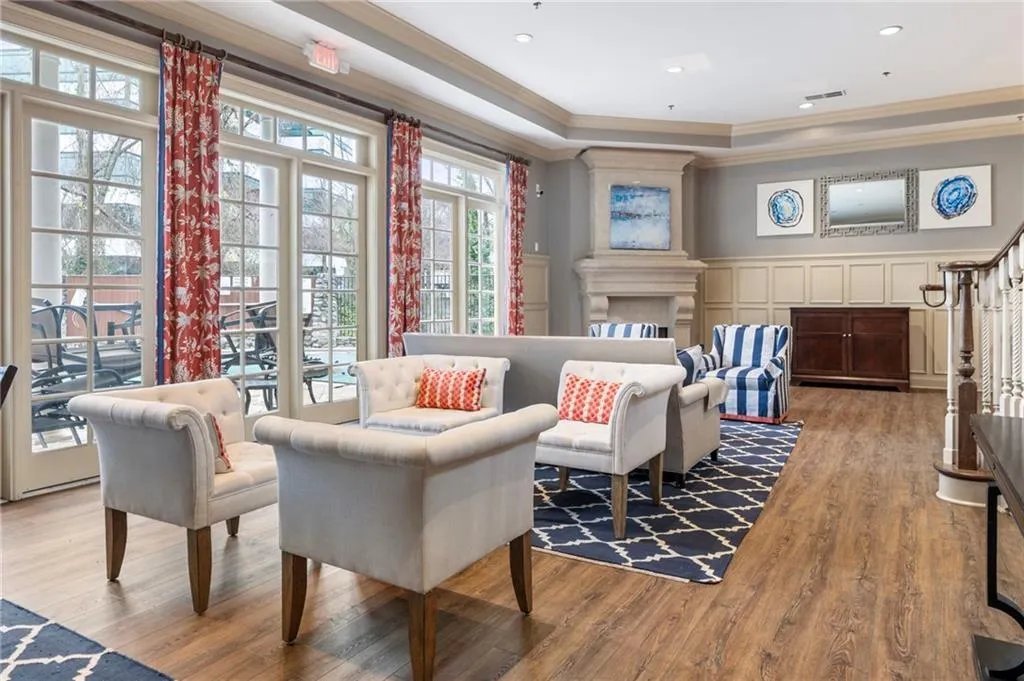 Living area featuring ornamental molding, a tray ceiling, a decorative wall, wood finished floors, and wainscoting