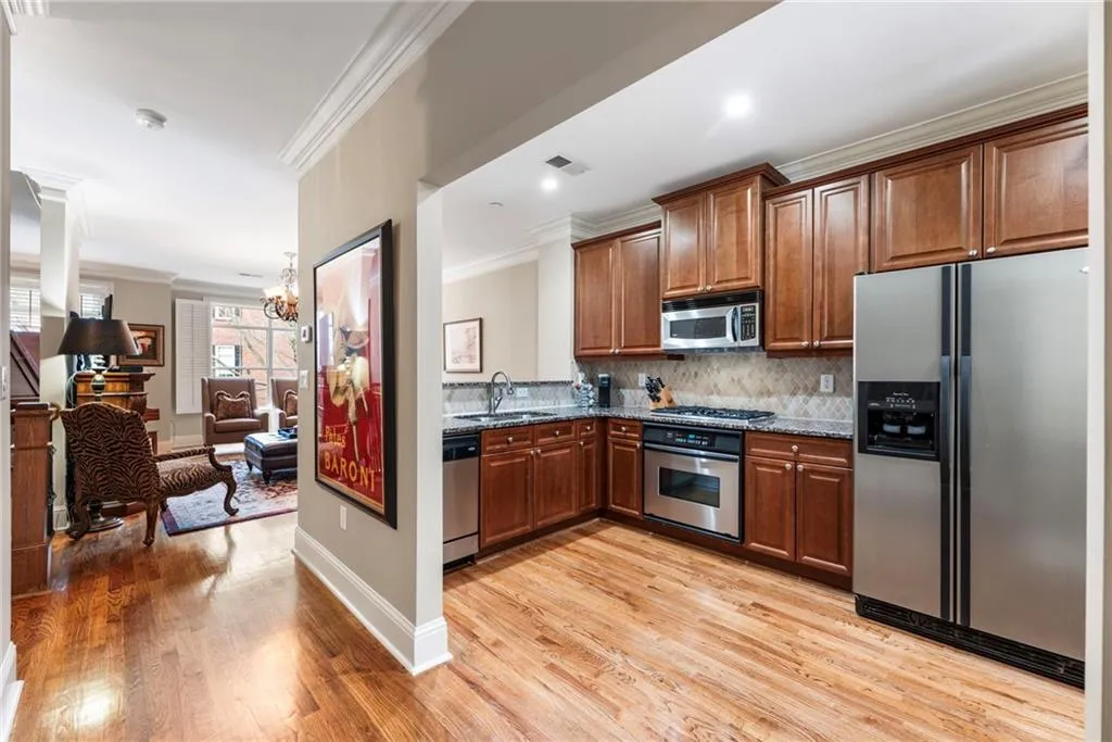 Kitchen featuring stainless steel appliances, ornamental molding, dark stone counters, light wood-style floors, and a chandelier