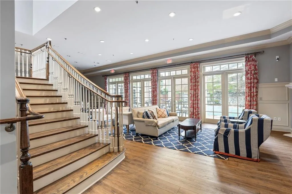 Living room featuring hardwood / wood-style floors, crown molding, a decorative wall, plenty of natural light, and a wainscoted wall