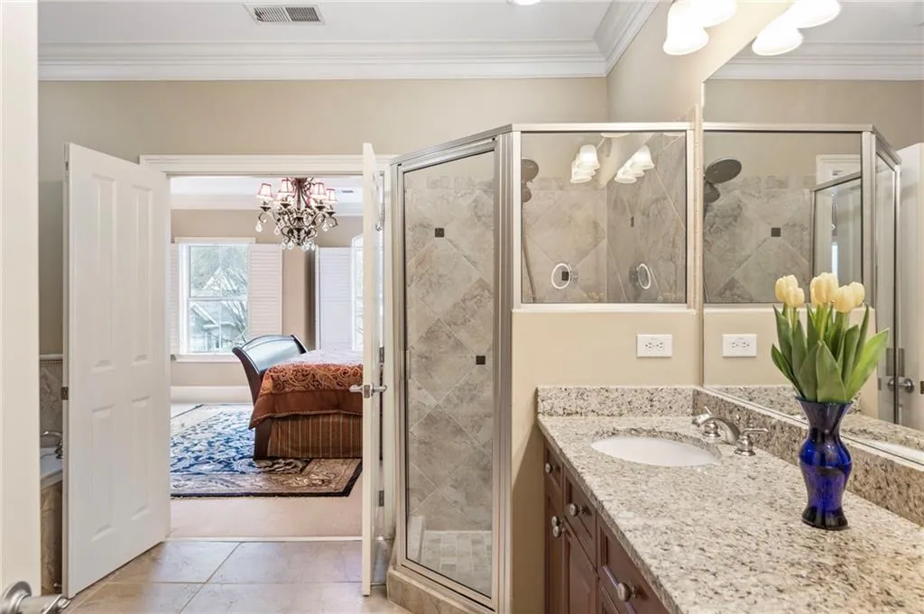 Full bathroom with ornamental molding, vanity, hanging lights, connected bathroom, and a stall shower