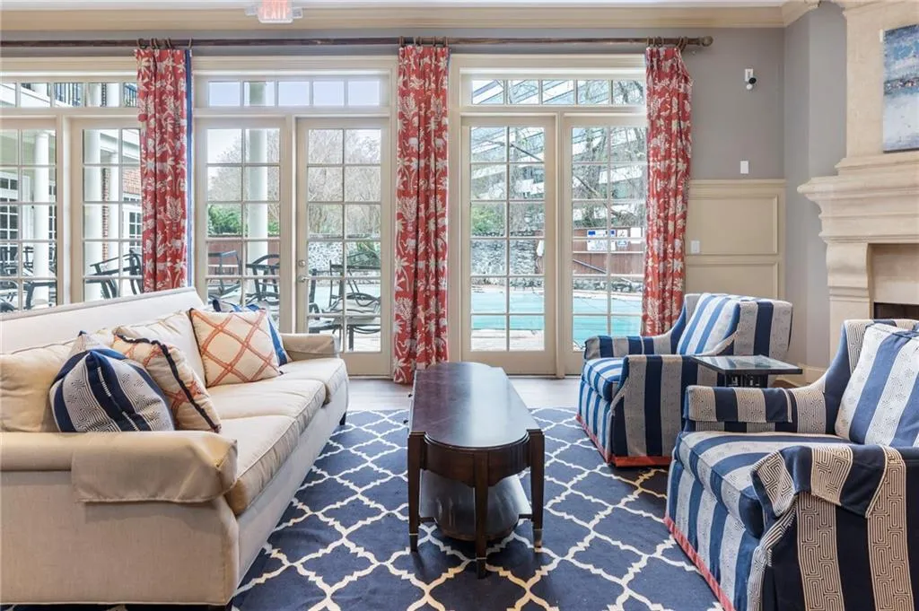 Living room featuring a fireplace, a decorative wall, wainscoting, french doors, and wood finished floors