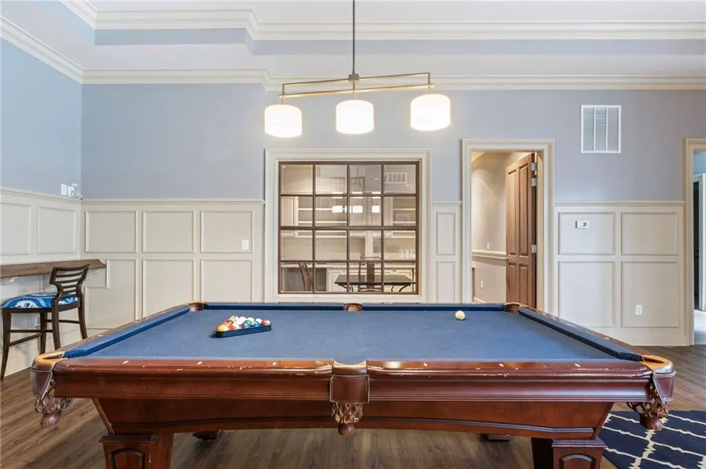 Rec room featuring a decorative wall, ornamental molding, a wainscoted wall, pool table, and dark wood-style floors