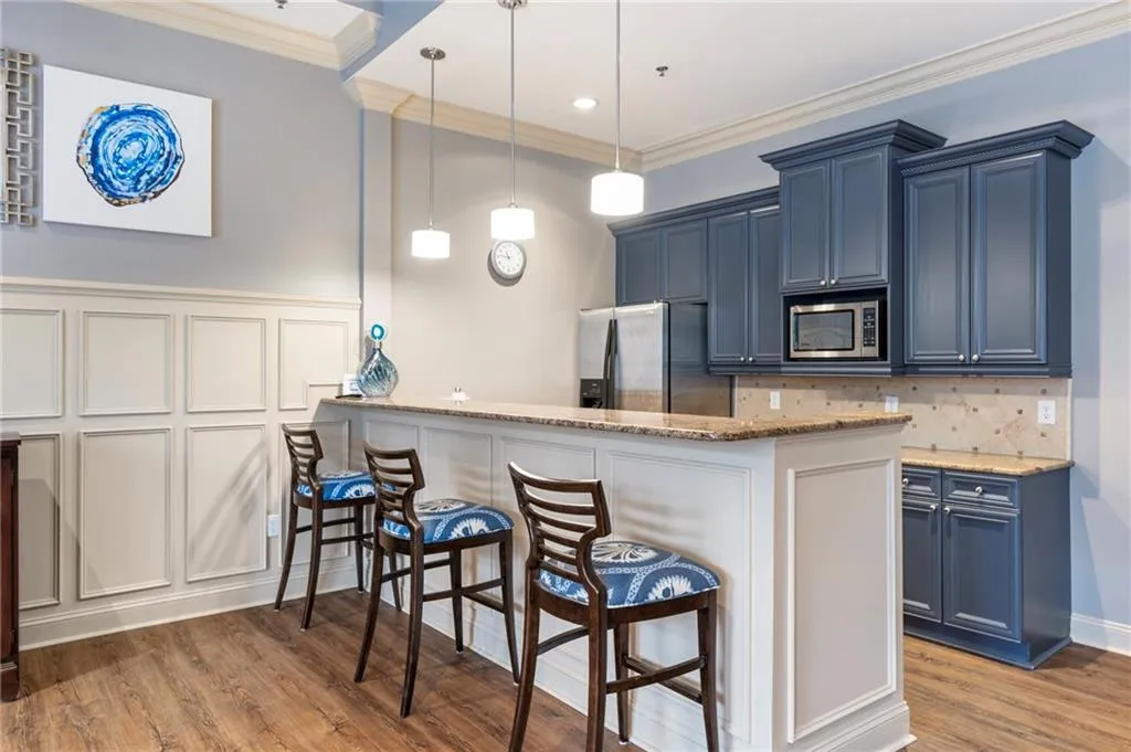 Kitchen featuring a breakfast bar area, ornamental molding, light stone counters, a peninsula, and stainless steel appliances