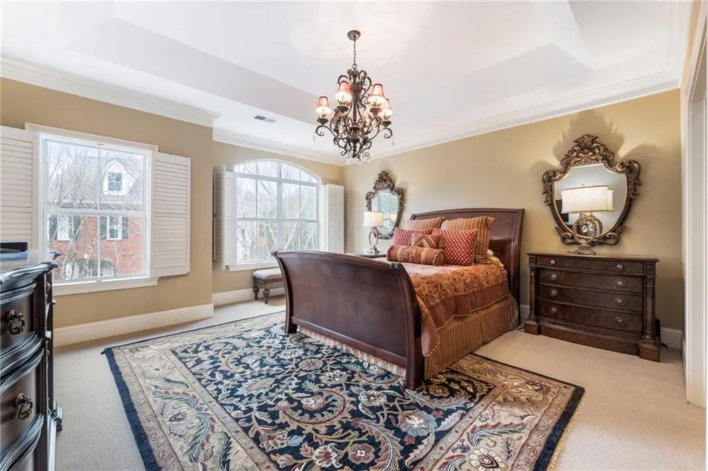 Bedroom with light carpet, crown molding, hanging lights, and a tray ceiling
