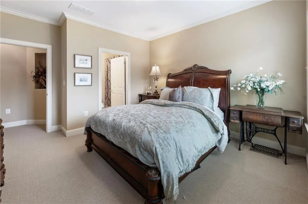 Bedroom with ornamental molding, light carpet, and connected bathroom