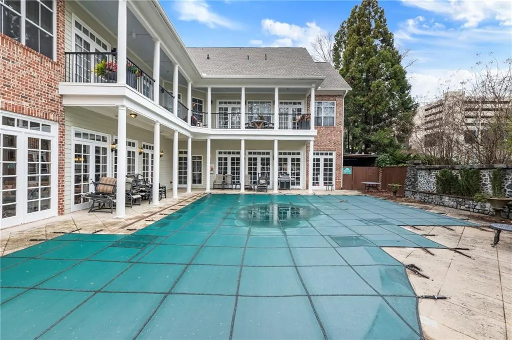 View of swimming pool featuring french doors, patio surround, and a balcony