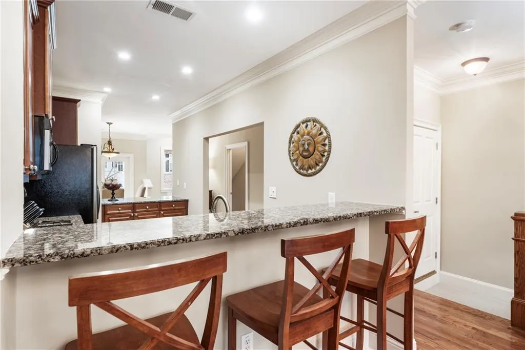 Kitchen featuring a breakfast bar area, a peninsula, dark stone counters, ornamental molding, and light wood-style floors