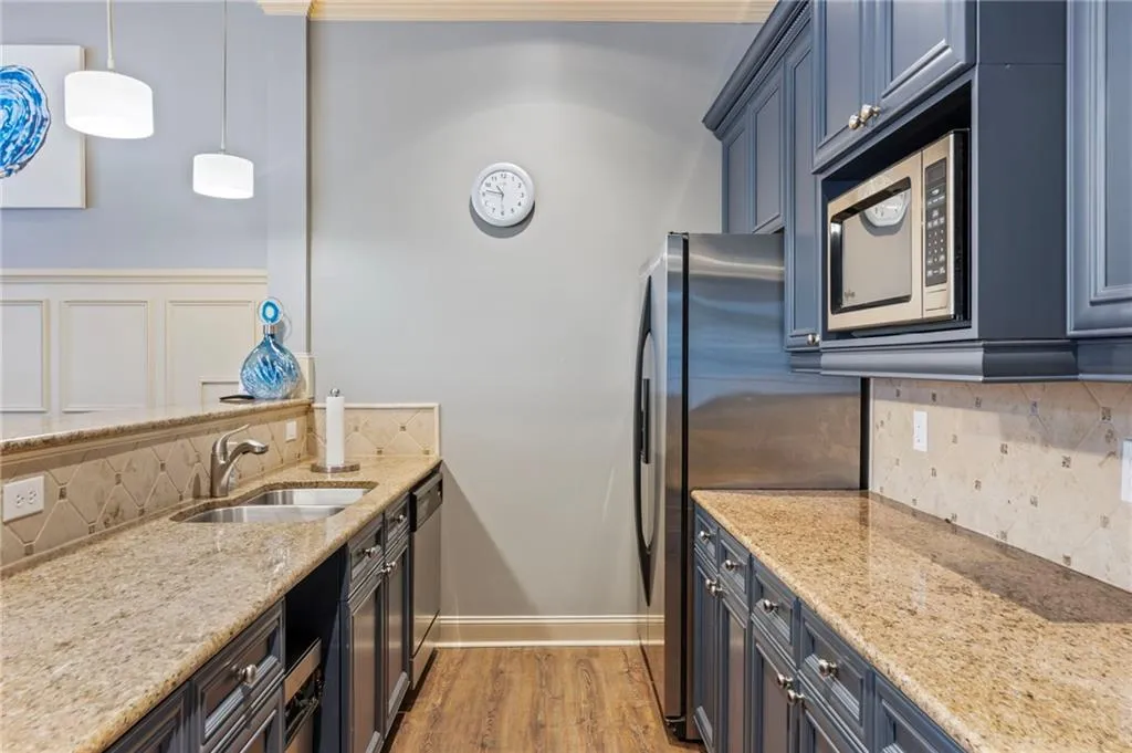 Kitchen featuring tasteful backsplash, light stone countertops, stainless steel appliances, and blue cabinetry