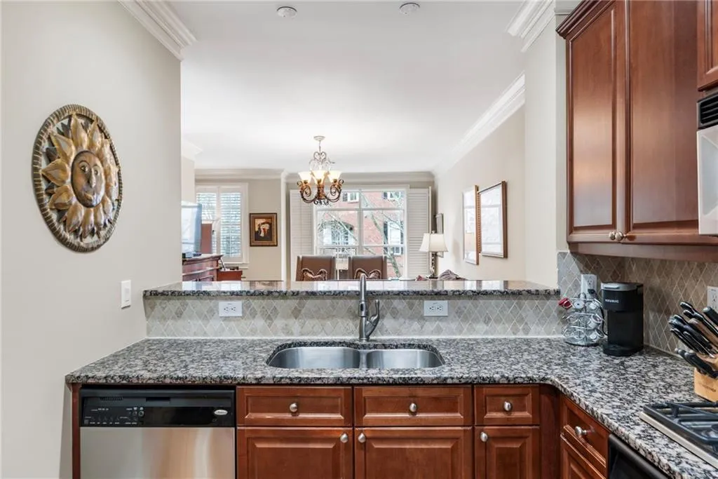 Kitchen featuring dark stone counters, stainless steel appliances, ornamental molding, decorative backsplash, and a chandelier