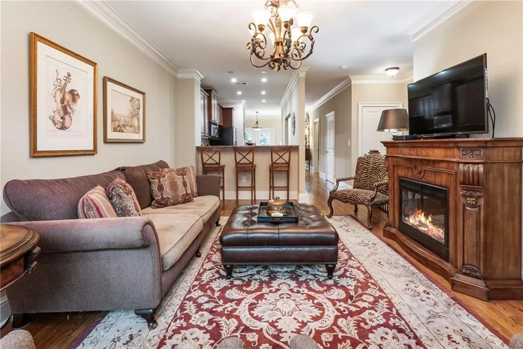 Living area with light wood-style flooring, crown molding, a glass covered fireplace, and suspended lighting