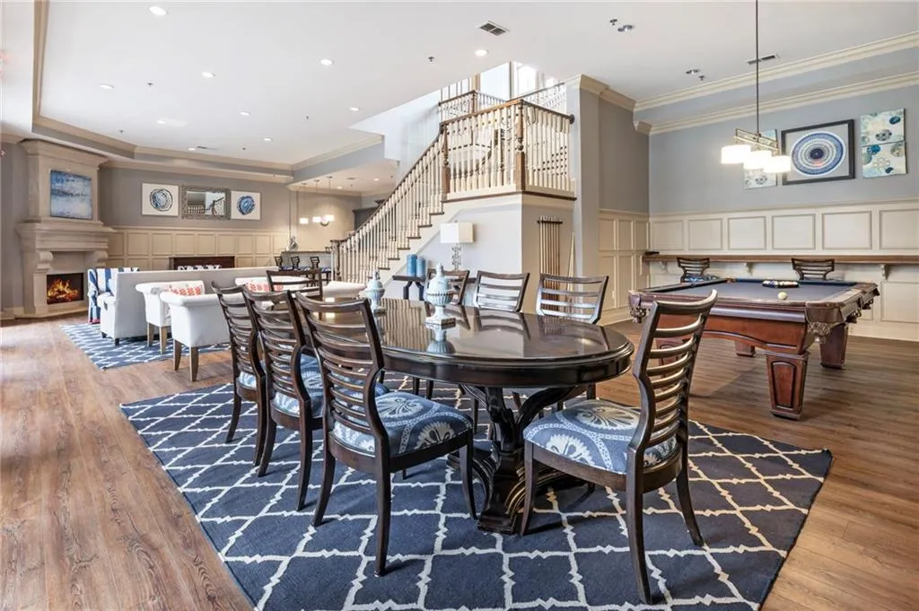 Dining room featuring crown molding, a decorative wall, light wood-type flooring, a lit fireplace, and pool table