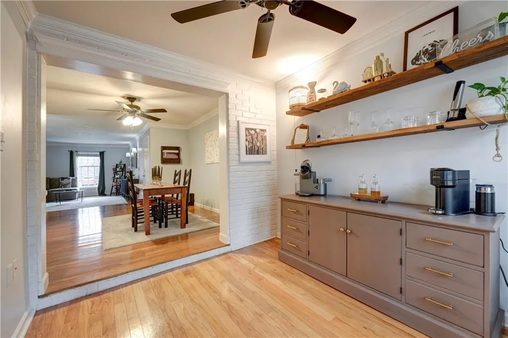 Bonus room featuring exposed brick, open shelves, and hardwood floors