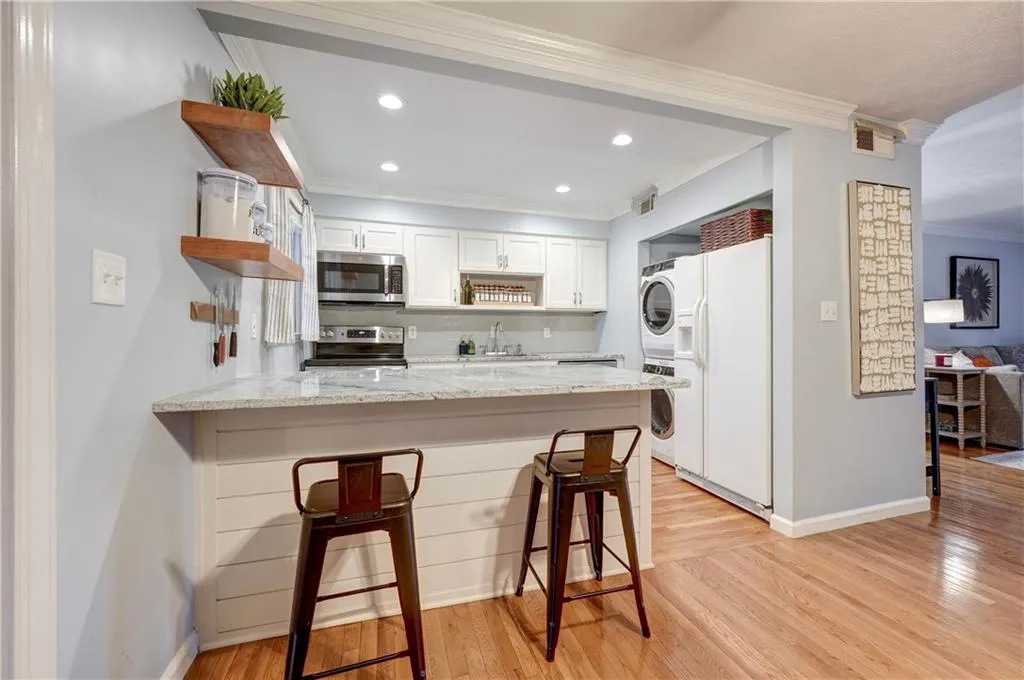 Recessed lighting in kitchen with new white cabinets and hardwood floors