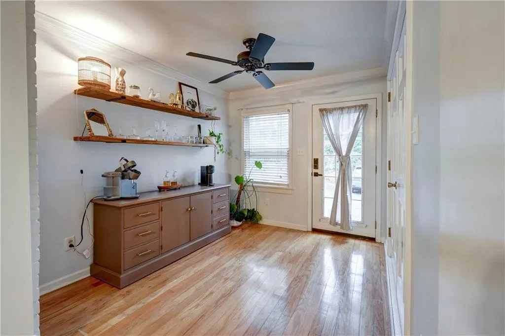 Bar with open shelves, hardwood floors, and crown molding
