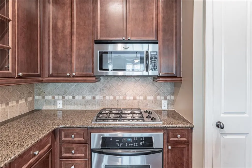 Kitchen featuring rich wood cabinetry, granite countertops, stainless steel appliances, a gas cooktop, and a decorative tile backsplash