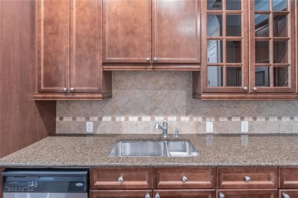 Kitchen featuring wood-finish cabinetry, granite countertops, stainless steel double basin sink, and an integrated dishwasher