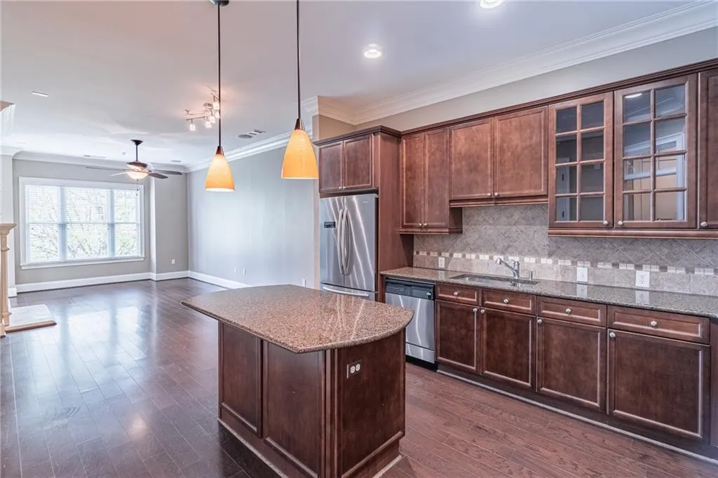 Open-concept kitchen featuring dark wood cabinetry, stainless steel appliances, granite countertops, and a tiled backsplash