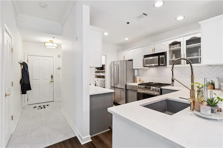 Kitchen featuring white cabinetry, kitchen peninsula, premium appliances, separate washer and dryer, and dark hardwood / wood-style flooring