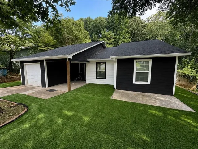 Contemporary exterior featuring black and white siding, a single-car garage, and a covered carport entrance