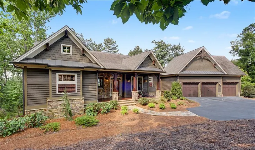 Craftsman-style residence featuring a dark green siding exterior with stone accents