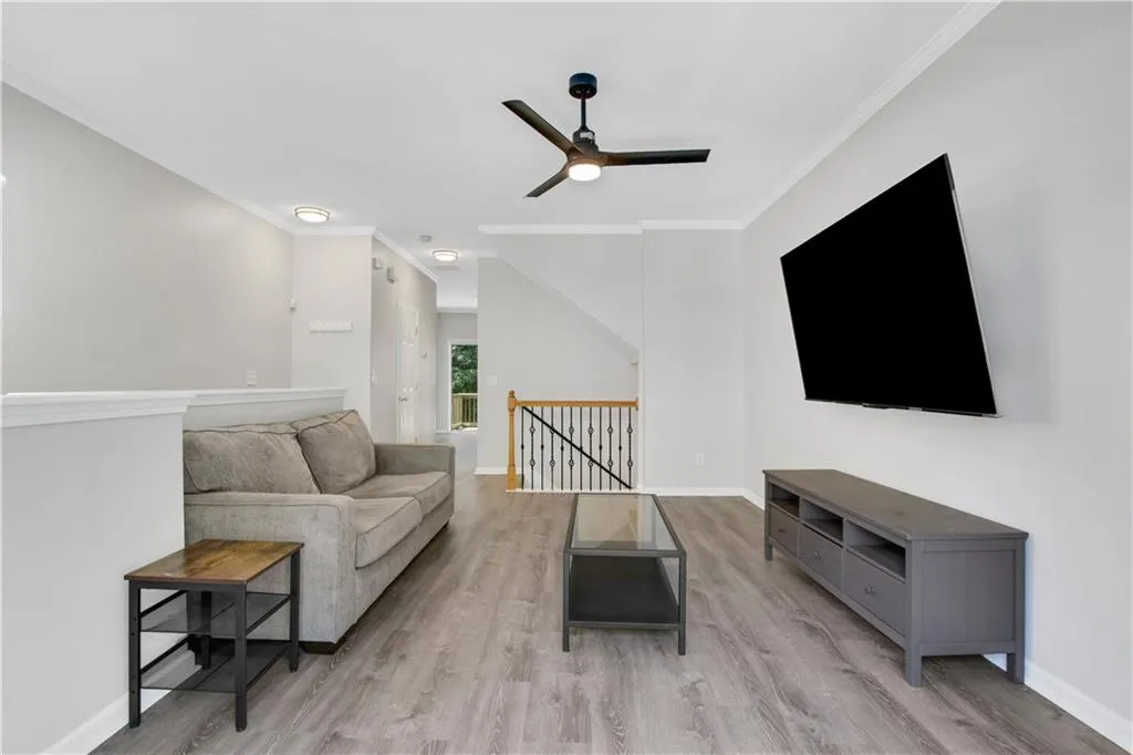 Living room with ceiling fan, wood finished floors, and ornamental molding