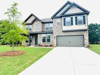 Two-story residence featuring a brick facade with complementary siding accents, a two-car garage, an established tree, and a concrete driveway