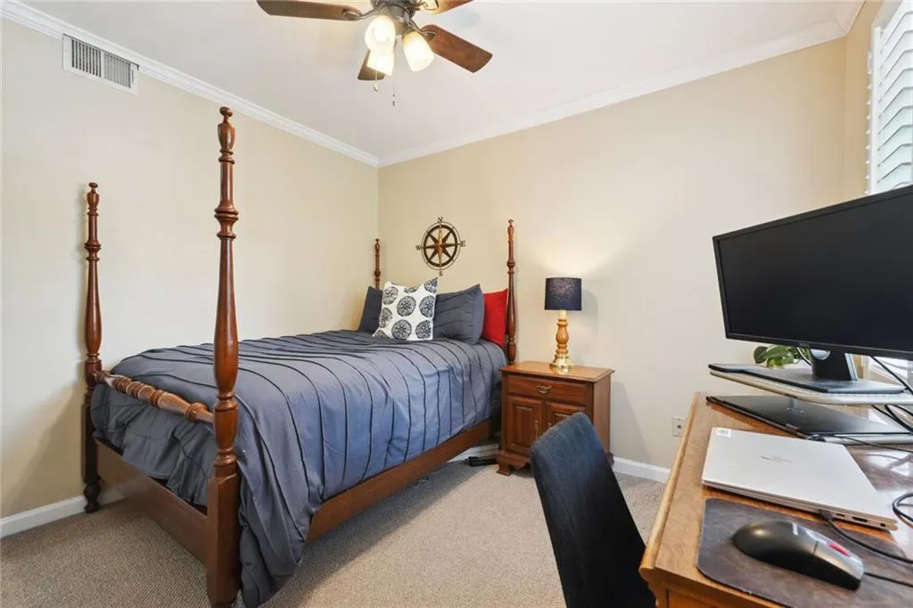 Carpeted bedroom featuring ornamental molding and ceiling fan