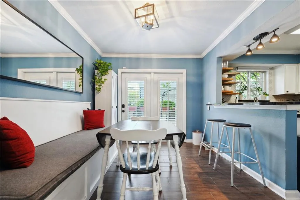 Dining area with crown molding, dark wood-style floors, and track lighting