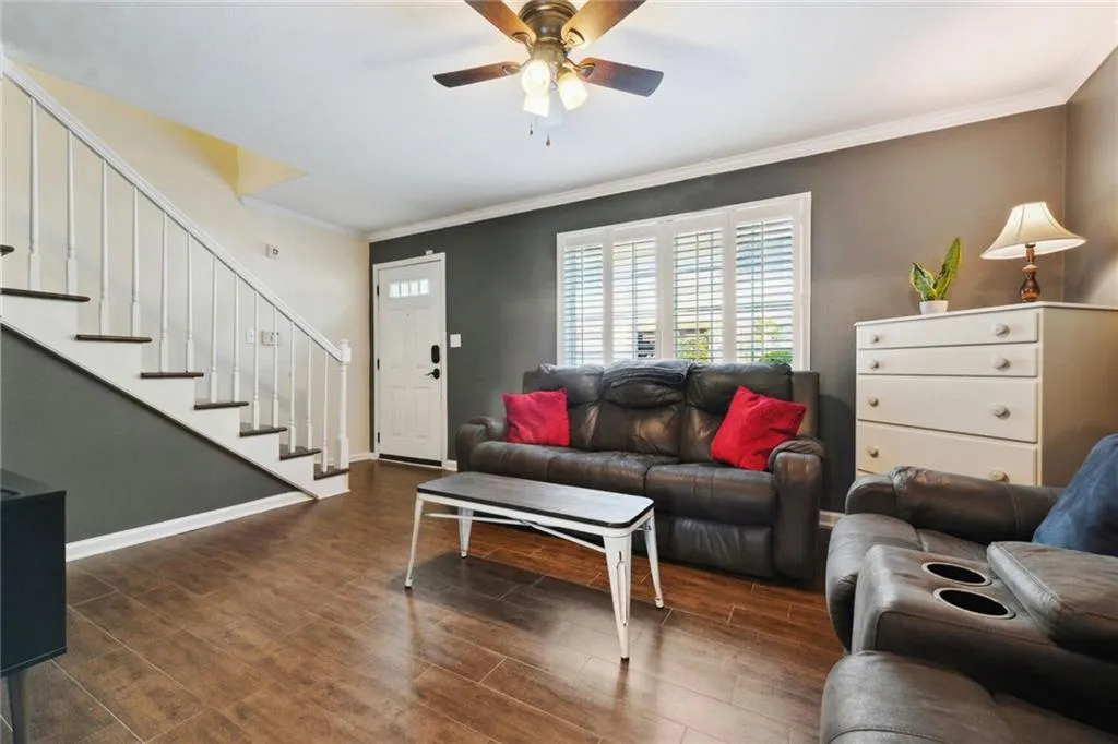 Living room featuring ornamental molding, dark wood-type flooring, and ceiling fan