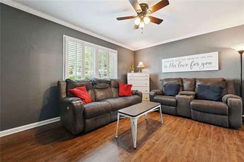 Living room featuring ceiling fan, crown molding, and wood-style flooring