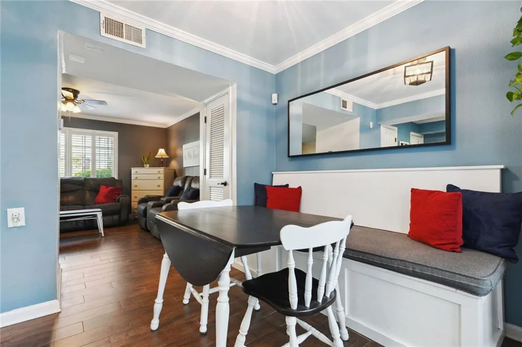 Dining room with wood-style flooring, ceiling fan, and crown molding