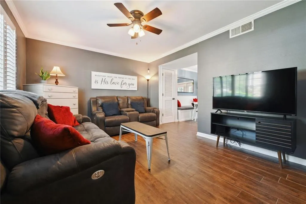 Living room with wood-type flooring, ceiling fan, and crown molding