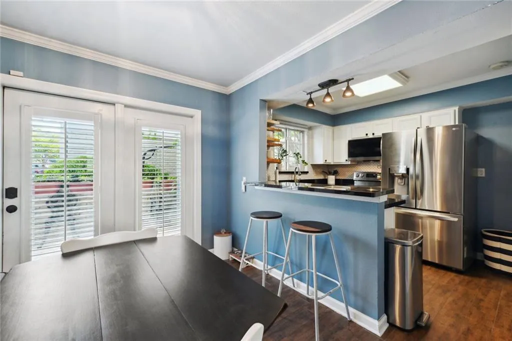 Kitchen with white cabinets, wood-style floors, kitchen peninsula, appliances with stainless steel finishes, and track lighting