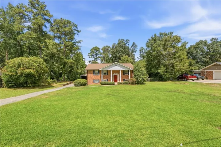 Brick-clad exterior with white columns, a red entry door, and dark shutters