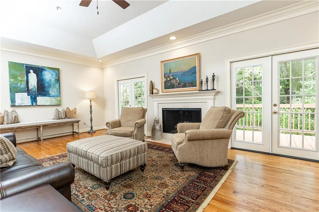 Spacious living room with fireplace opens onto a large deck with private, wooded view.
