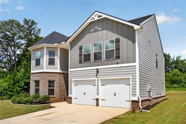 Contemporary two-story residence featuring a two-car garage, gray siding, and brick accents
