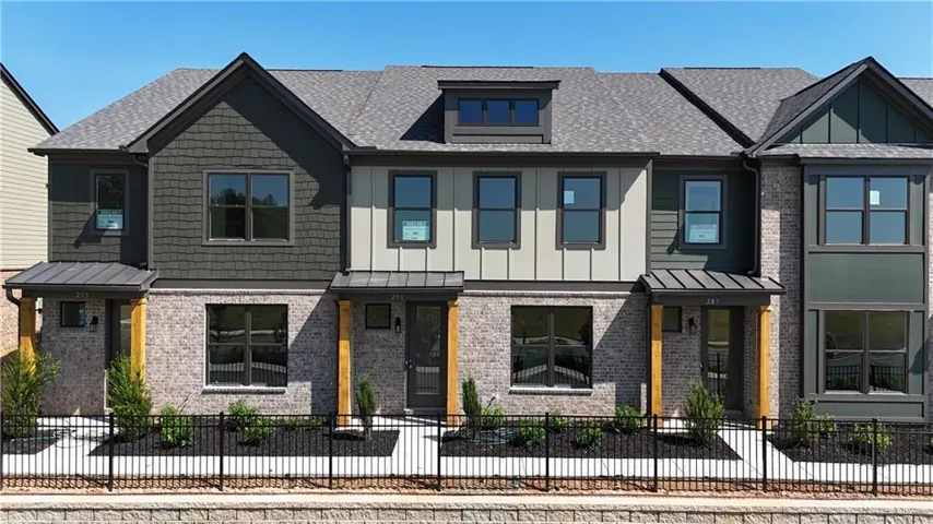 Contemporary townhome exterior featuring a mixed material facade, gabled rooflines, and multiple window styles