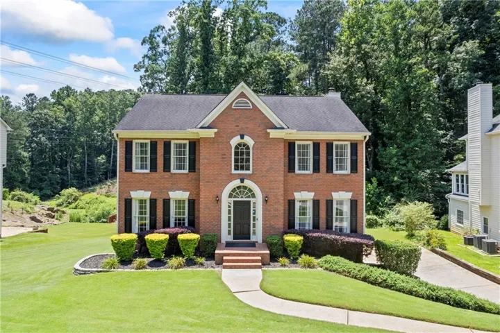 Colonial home with a front lawn, brick siding, a chimney, and a shingled roof