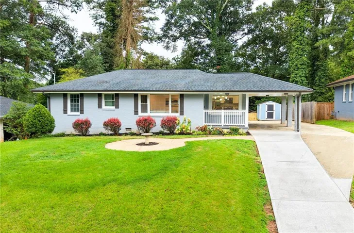 Charming single-story residence featuring a freshly paved concrete driveway and walkway leading to a covered front porch with white railings