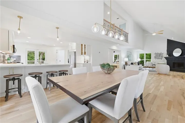 Hardwood flooring, vaulted ceilings, a fireplace, a kitchen island with built-in seating, and a second-story interior balcony
