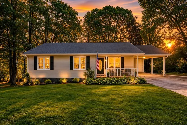 Ranch-style residence featuring light-colored siding and a dark shingle roof