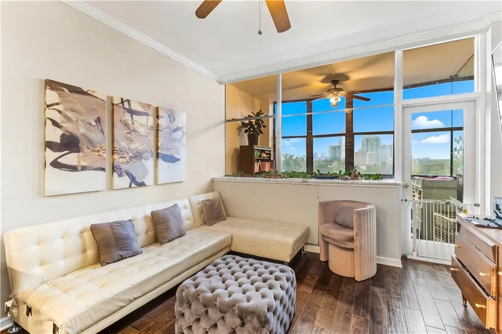 Living area with ceiling fan, crown molding, a view of skyline, dark wood-style floors, and healthy amount of natural light