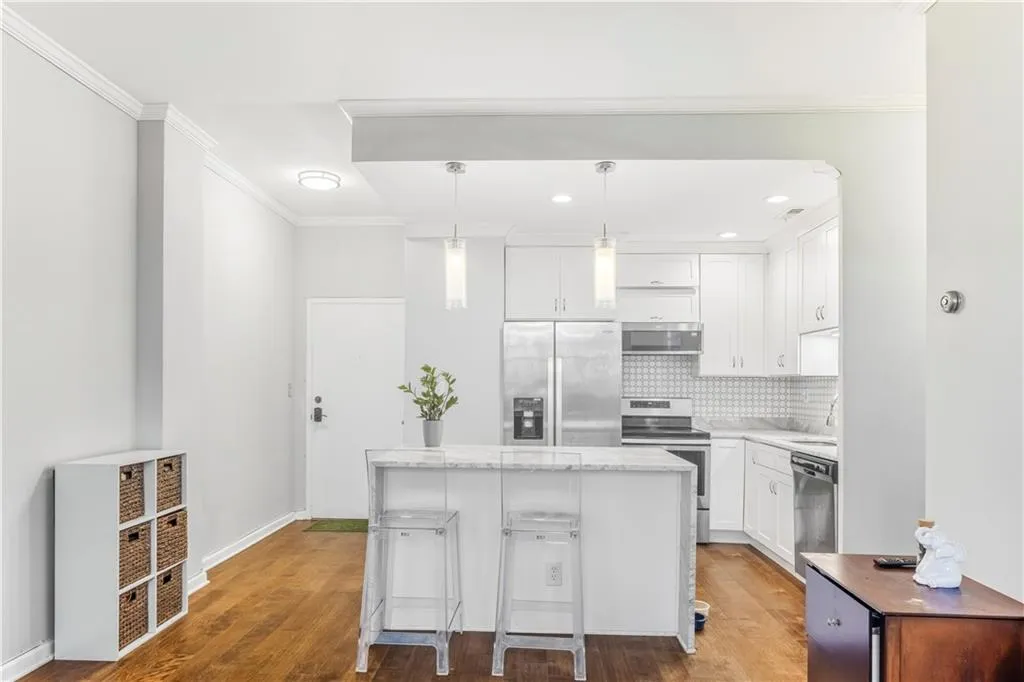 Kitchen with stainless steel appliances, white cabinets, ornamental molding, a kitchen island, and pendant lighting