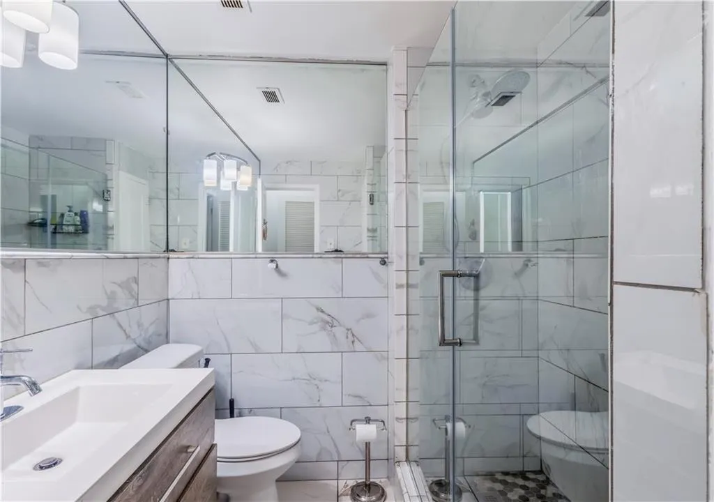 Bathroom featuring vanity, tile walls, and a stall shower