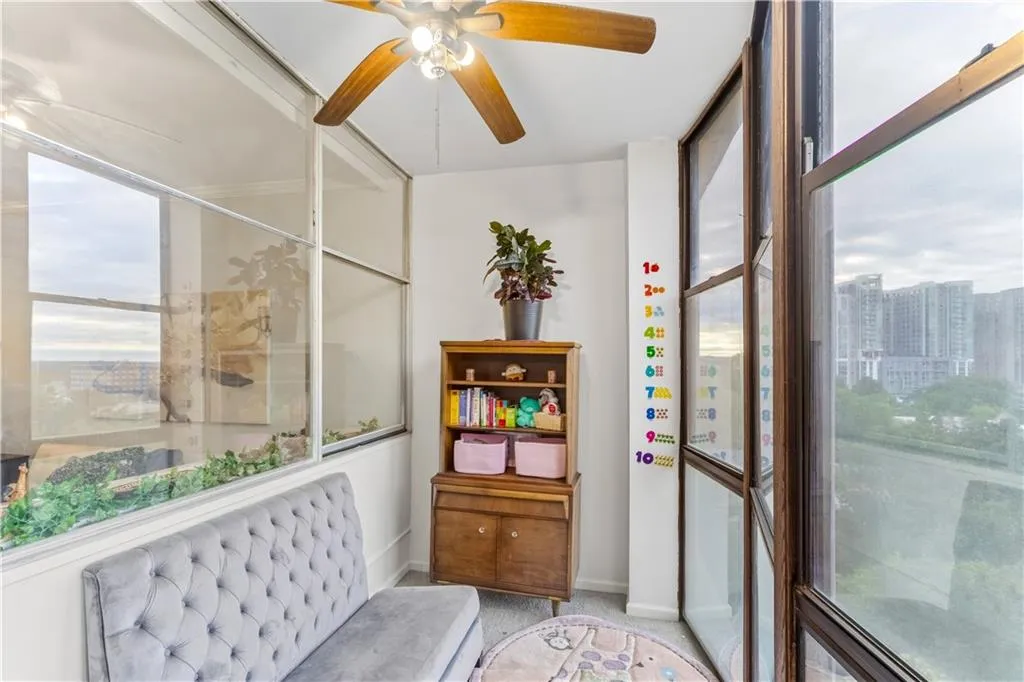 Living area with ceiling fan, light carpet, and floor to ceiling windows
