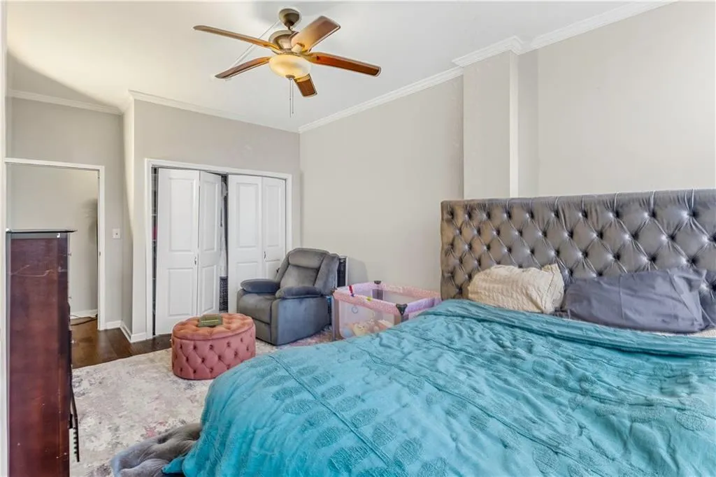 Bedroom with ornamental molding, a closet, wood finished floors, and ceiling fan