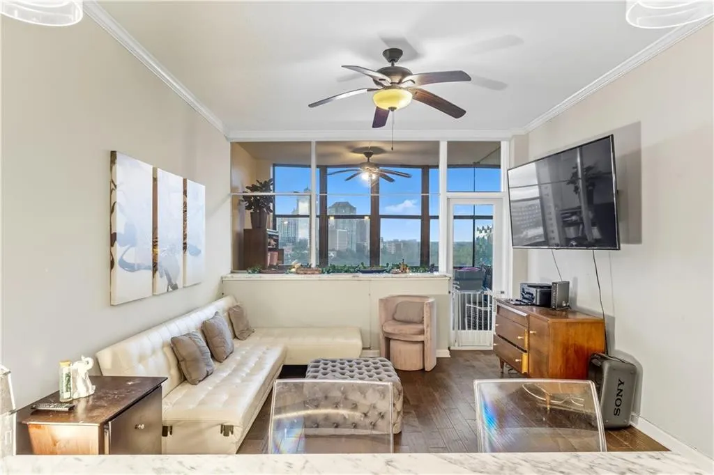 Living room with dark wood-type flooring, crown molding, and ceiling fan