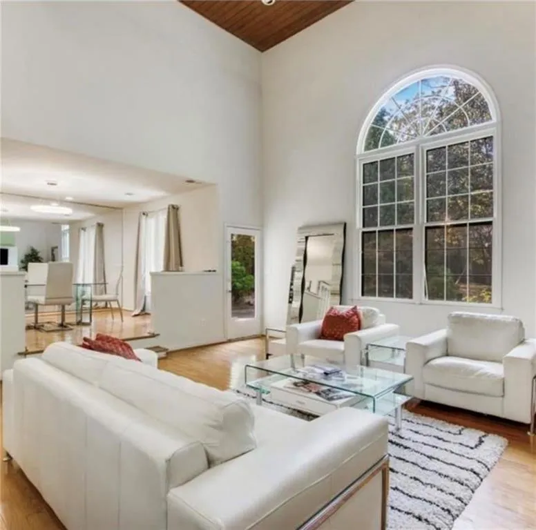 Living room with light wood-style flooring, wooden ceiling, and a towering ceiling